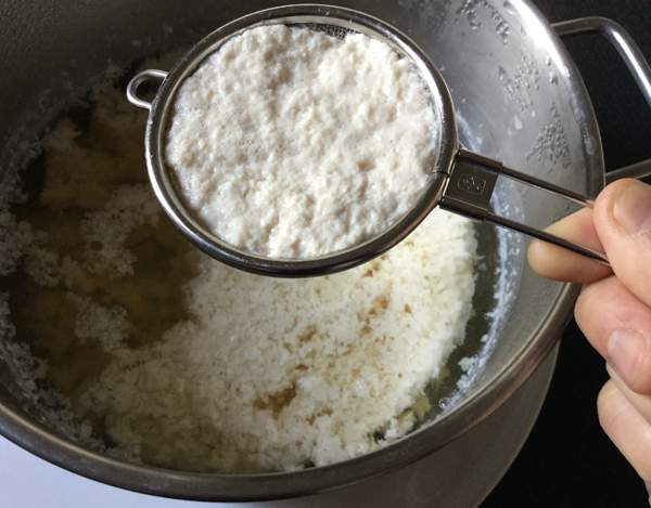 Prendere con un mestolo la parte solida e filtrare con un colino o un bicchiere di carta bucato, lasciare a sgocciolare per 5 minuti